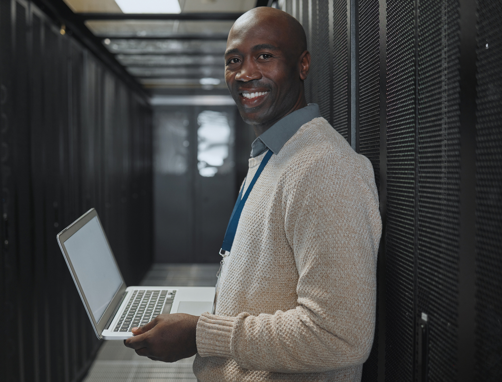 Happy man with laptop in server room